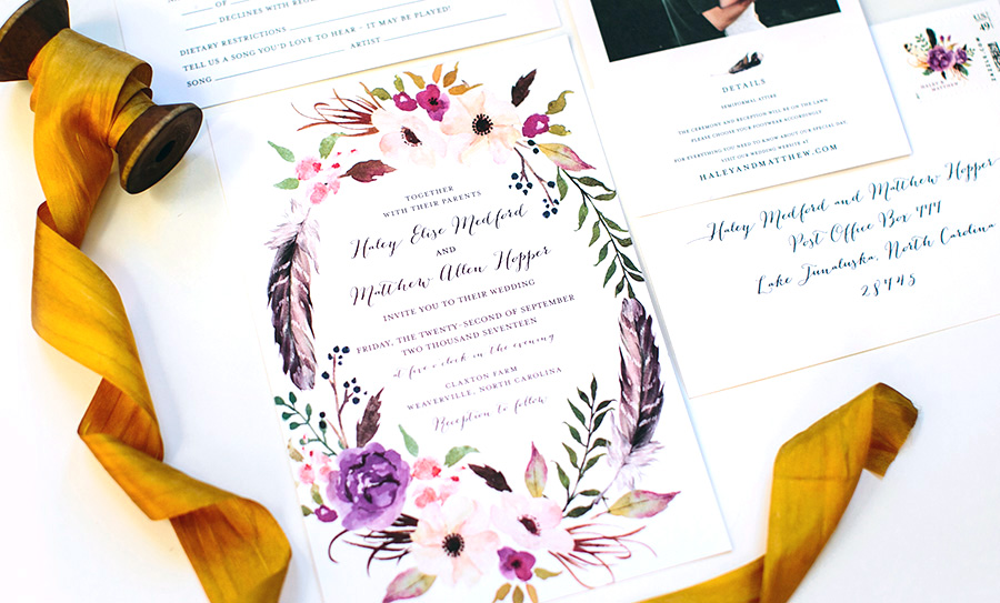 detail photograph of a wedding invitation decorated with flowers and feathers